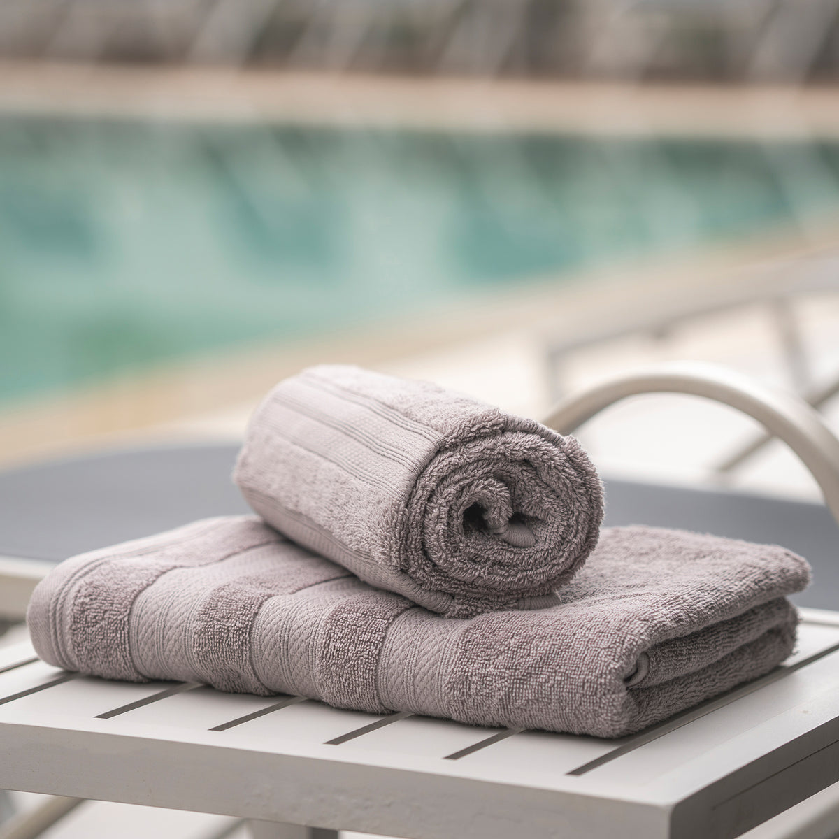 Ash Grey Melluva Turkish cotton towel rolled on a poolside lounger