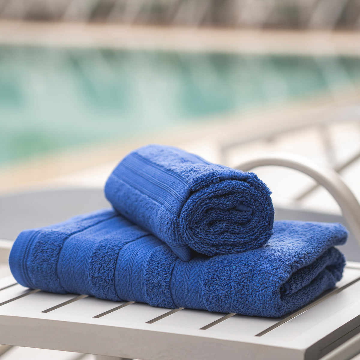 Denim Melluva Turkish cotton towel rolled on a poolside lounger