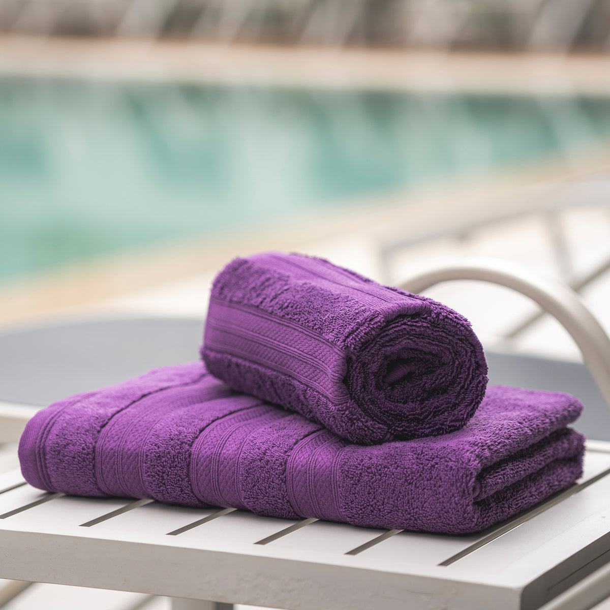Plum Melluva Turkish cotton towel rolled on a poolside lounger